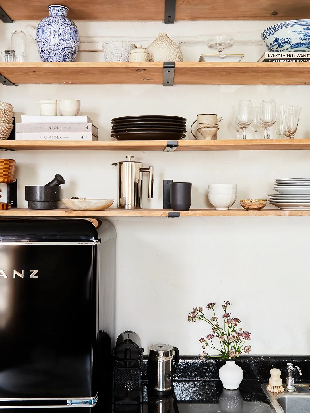 Close up of kitchen with open shelves and black fridge