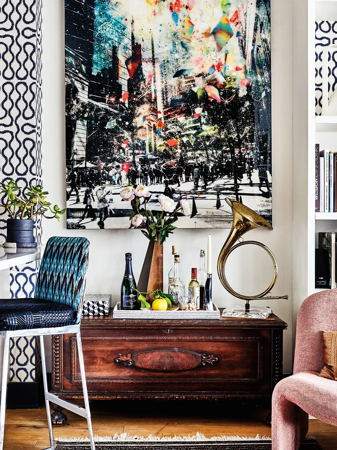Artwork and chest between kitchen and bookshelf